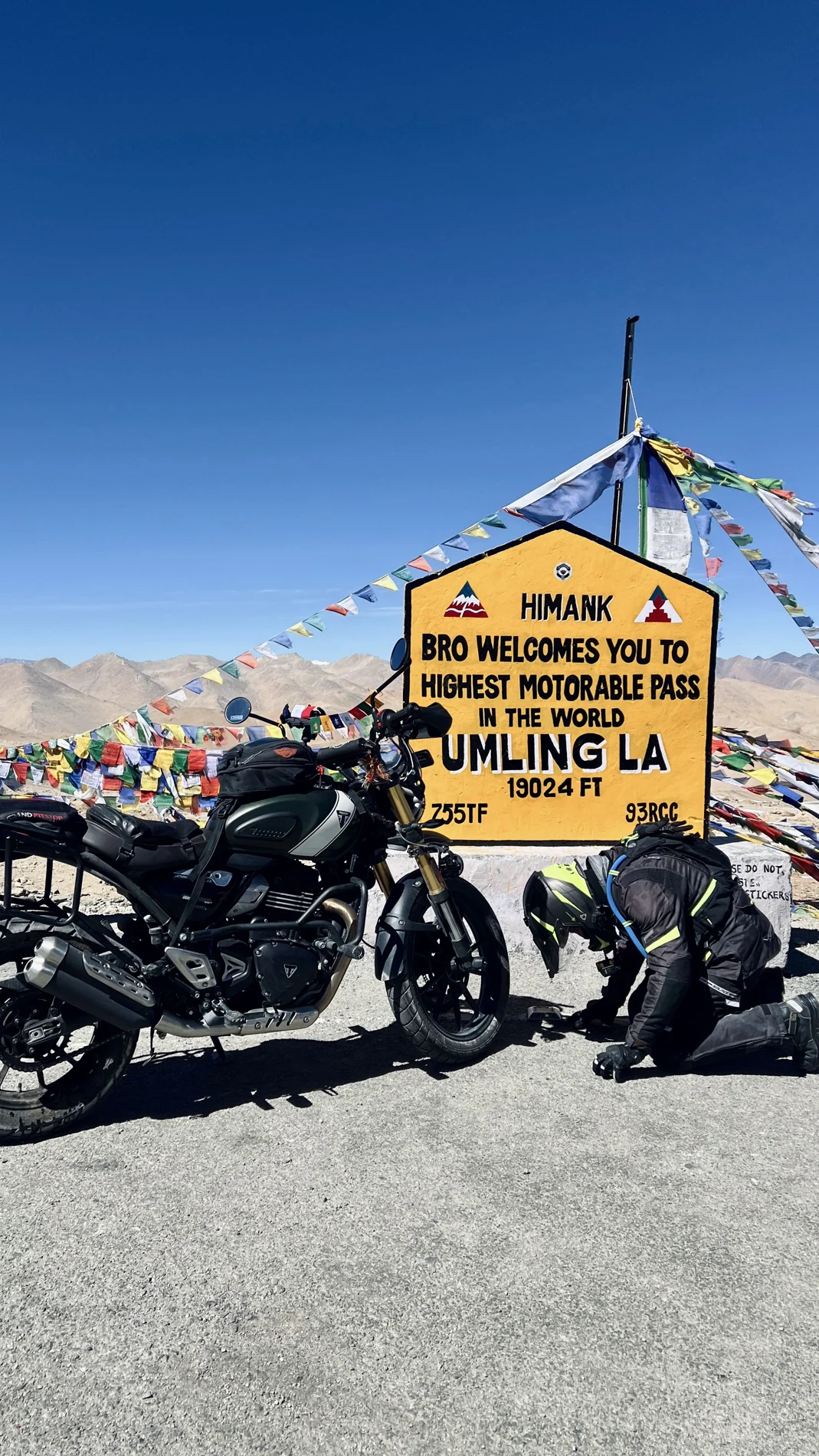Motorcycle and rider beside the Umling La sign